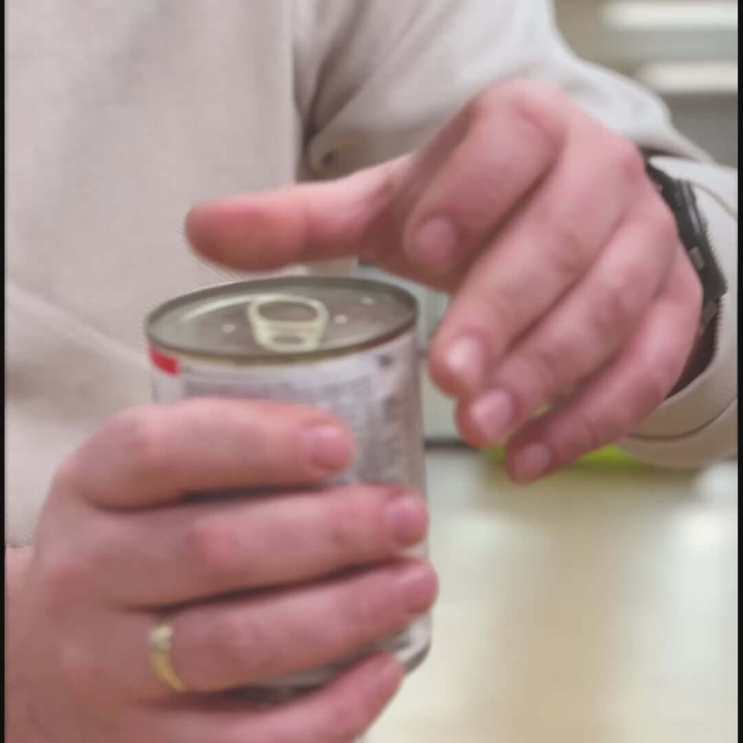 Person opening a can, showcasing hands and can lid mechanism.